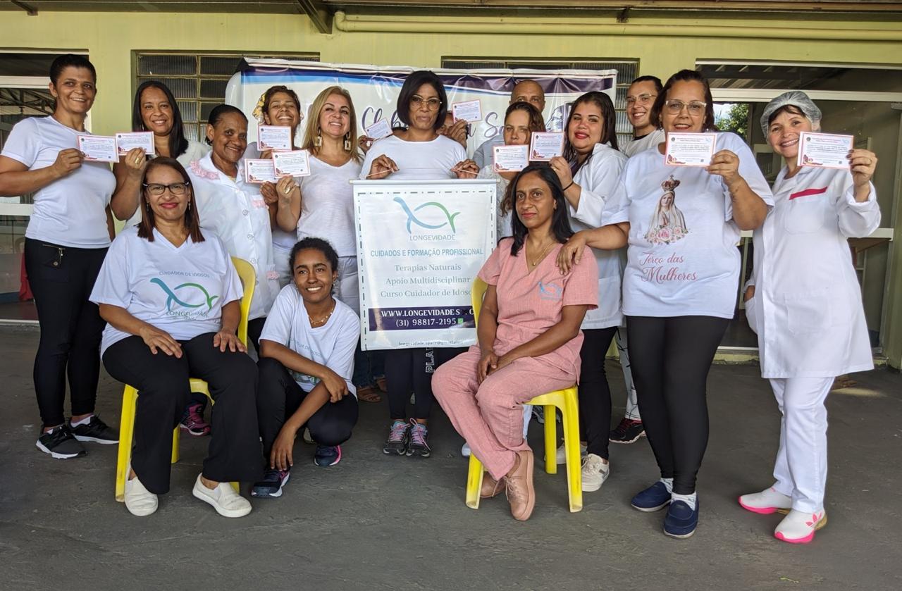 Turma de alunas da Longevidade com professoras e banner institucional